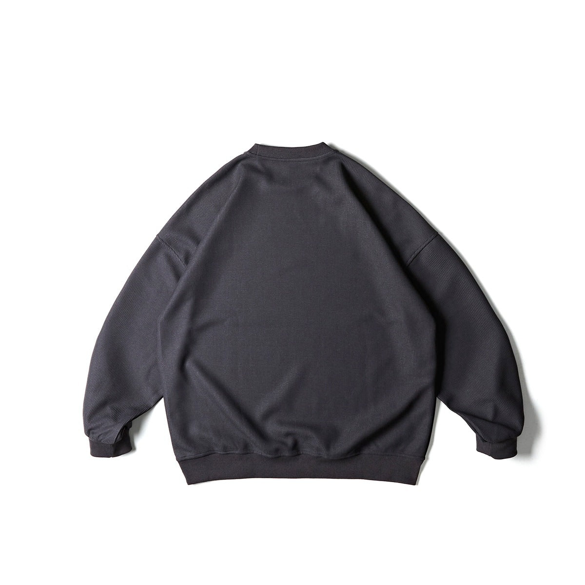 Back view of a charcoal gray textured crewneck sweatshirt with dropped shoulders and ribbed cuffs and hem.