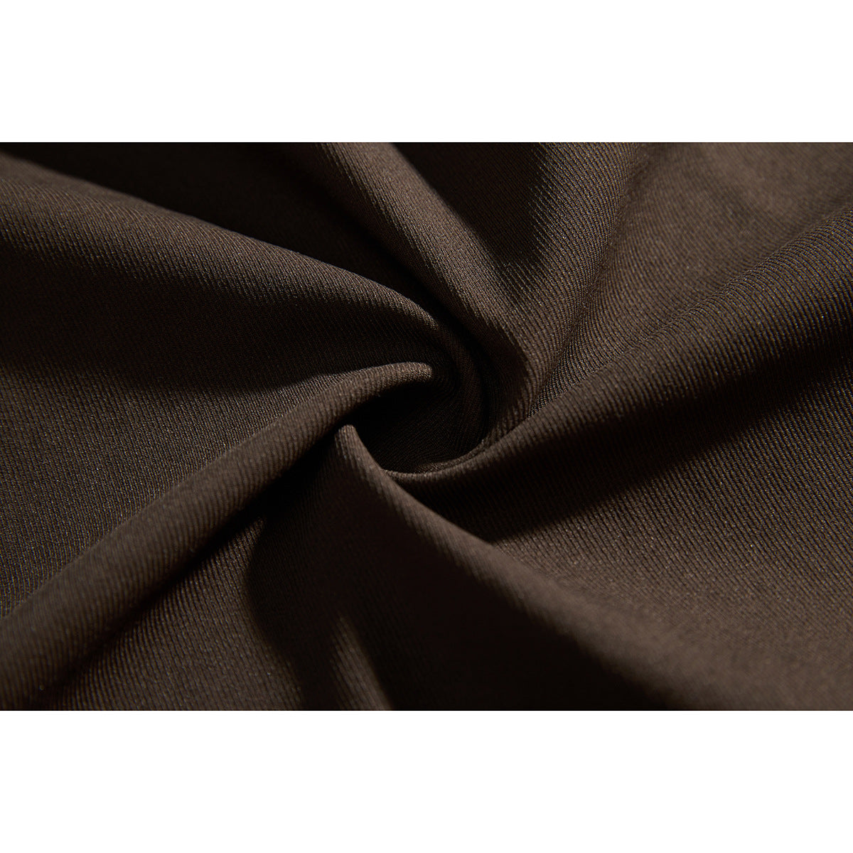 Macro view of dark brown jacket fabric gathered into folds, showing its fine diagonal texture.