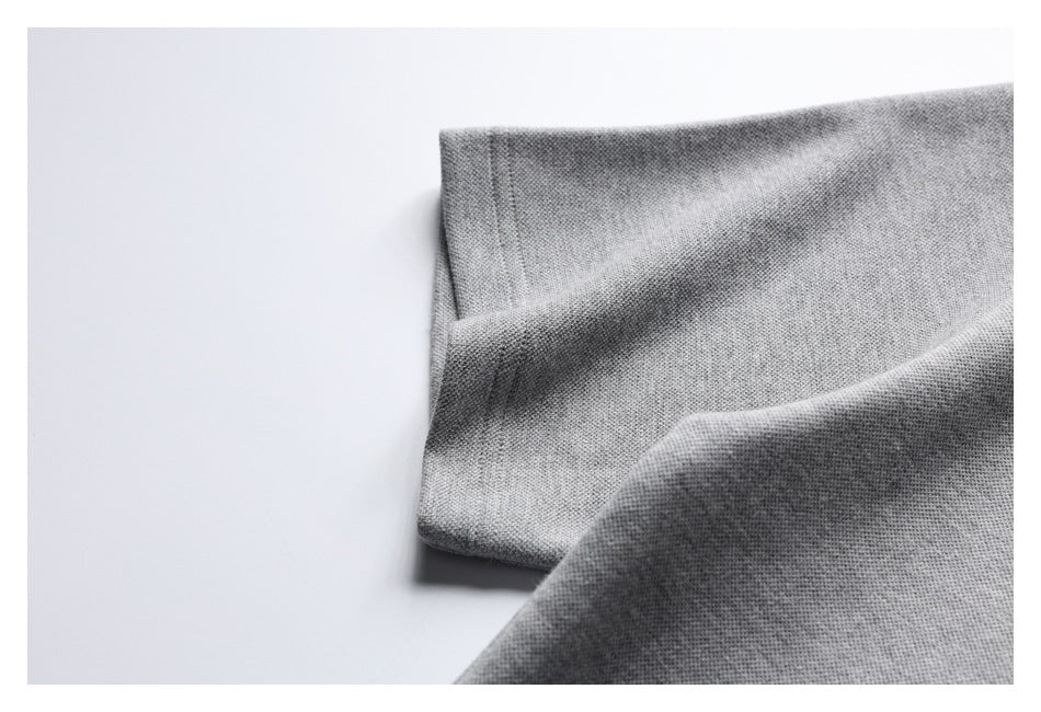 Close-up of a folded edge on a light gray garment, showing the fabric and stitching.