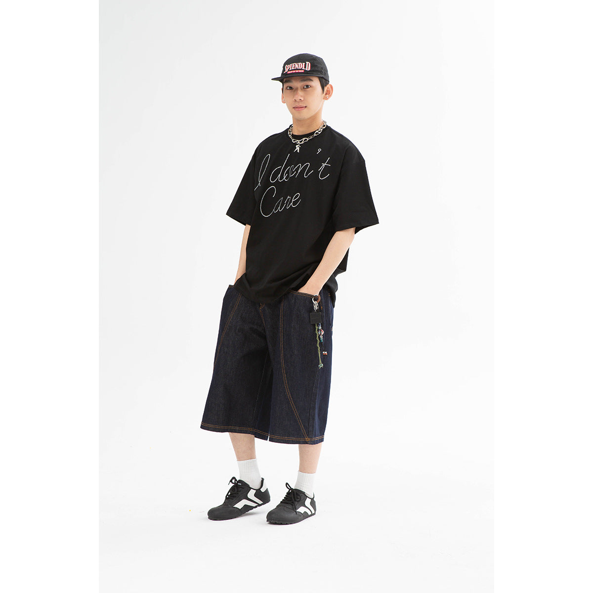 Model wearing an oversized black script-print T-shirt and dark indigo wide-leg denim shorts.