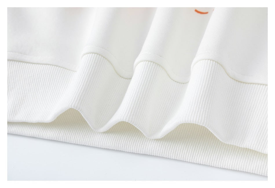 Close-up of a white garment's ribbed hem, with a small partial orange mark near the top edge.