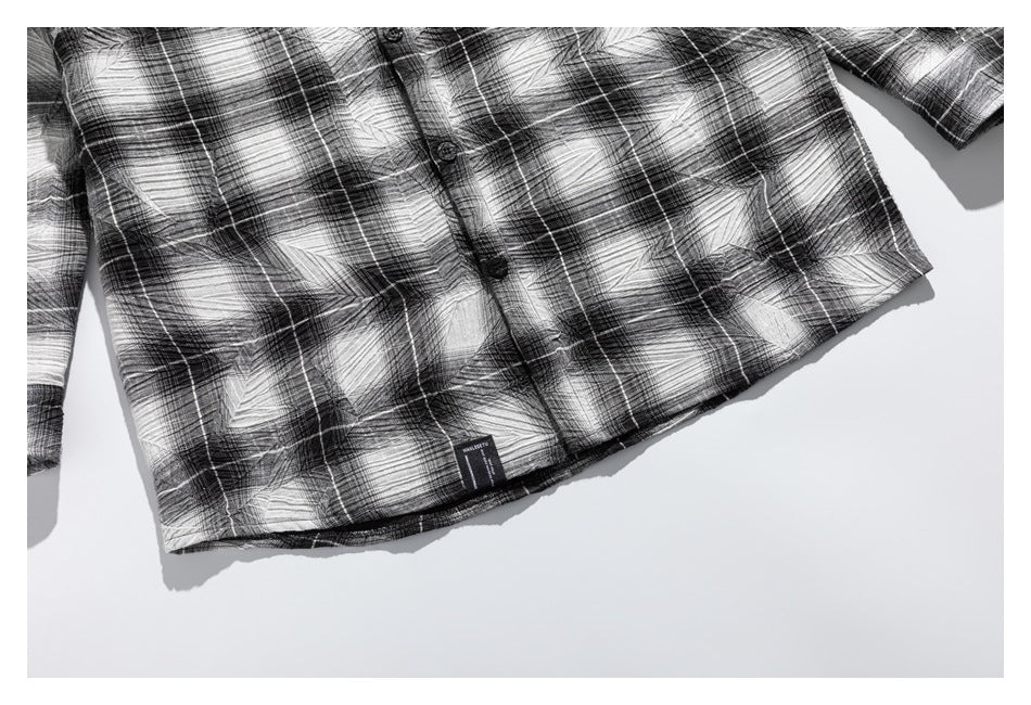 Partial flat-lay front view of a black-and-white plaid button-up shirt.