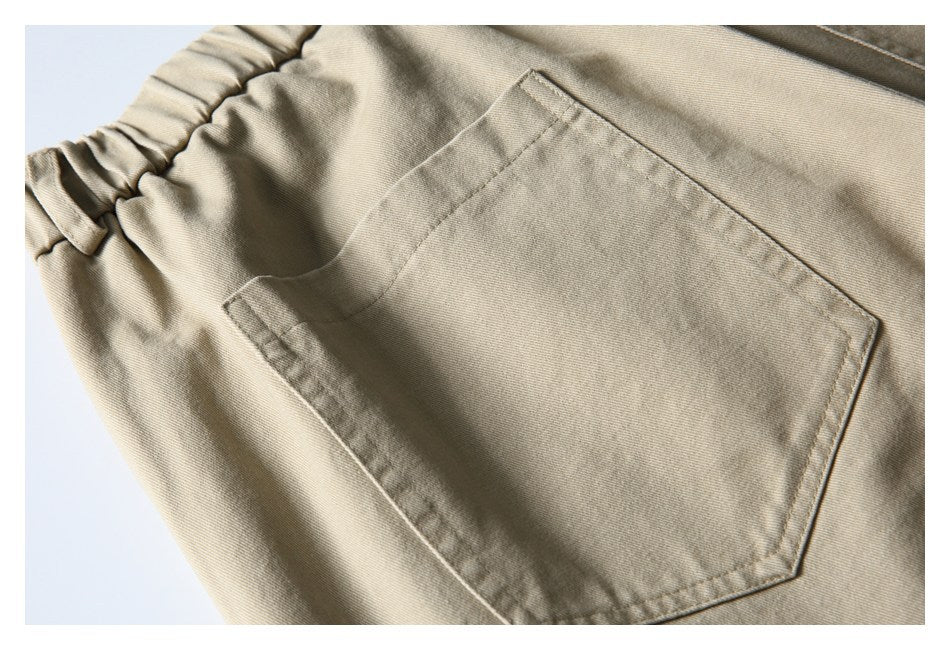 Close-up of a large stitched patch pocket on the back of beige shorts.