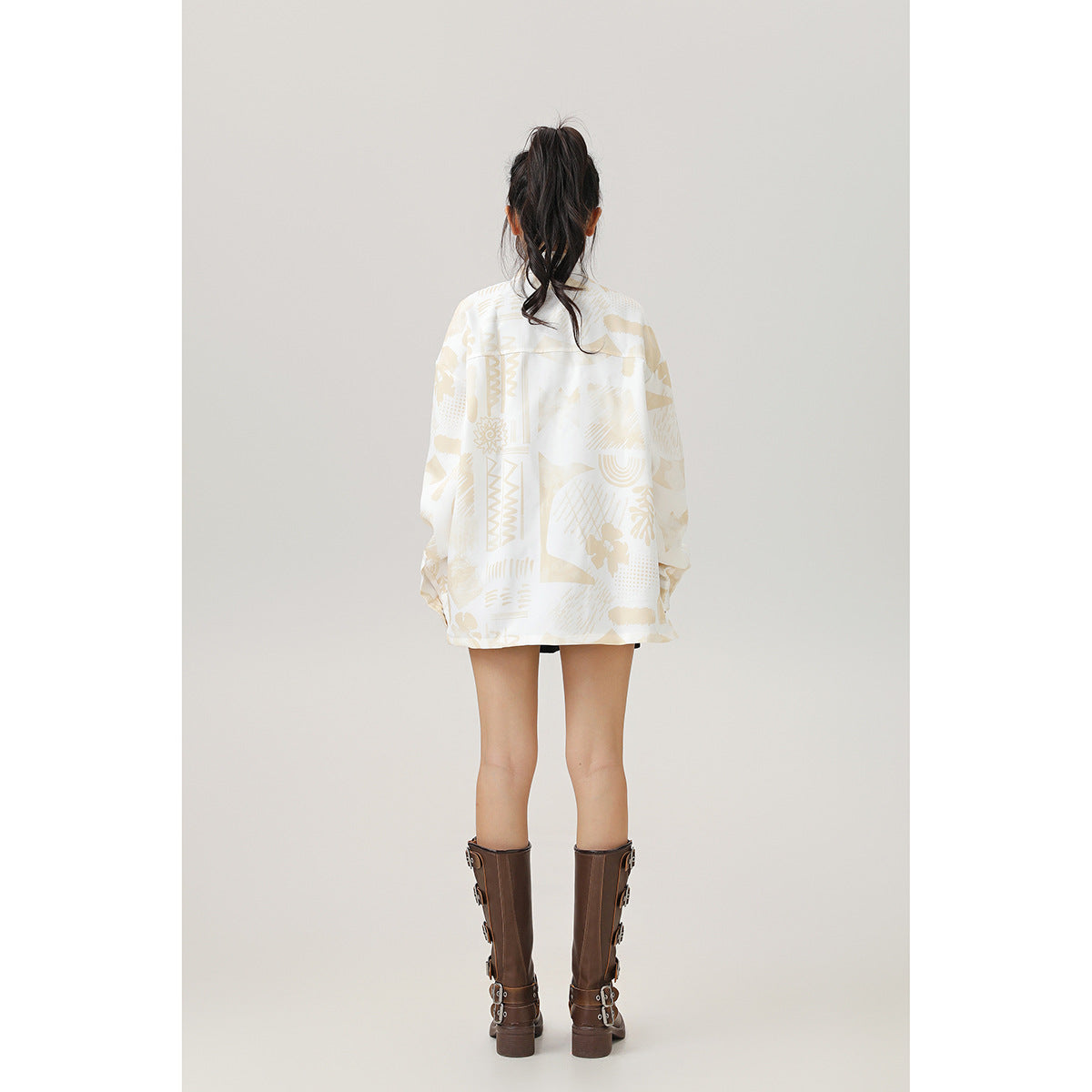 Back view of a model wearing an oversized cream shirt with a beige abstract print.