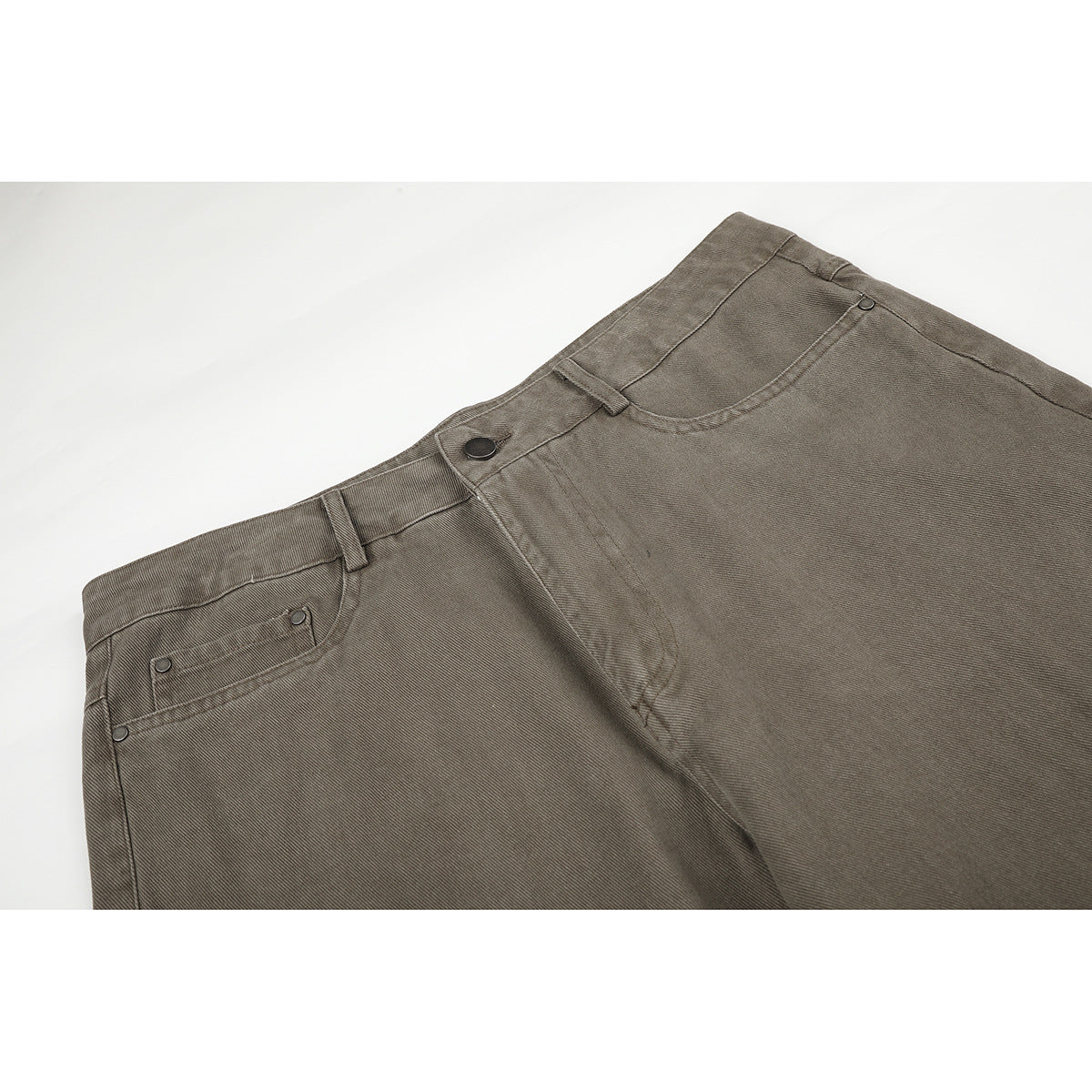 Close-up of taupe-gray pants showing the front waistband, button closure, fly, and curved pocket stitching.