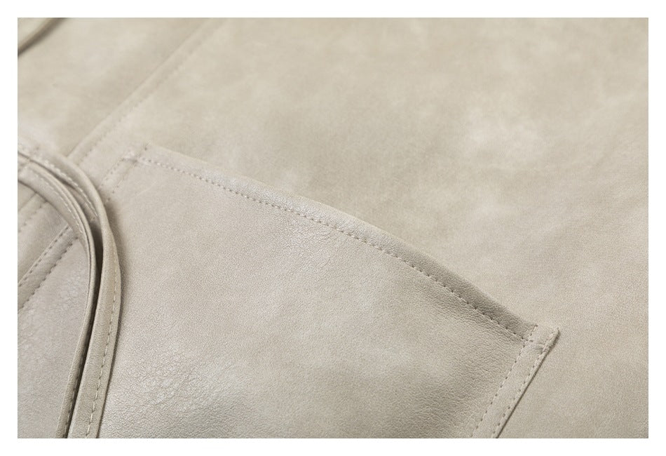 Close-up of a slanted pocket and stitched trim on a light taupe coat.