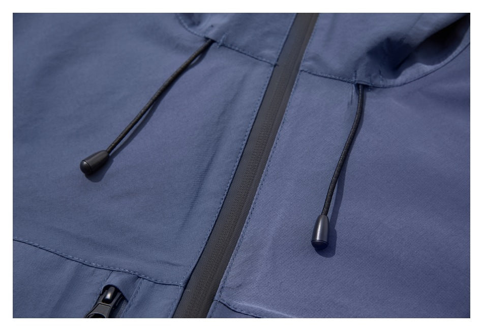 Close-up of a blue jacket hood with black drawcords and a central dark zipper.