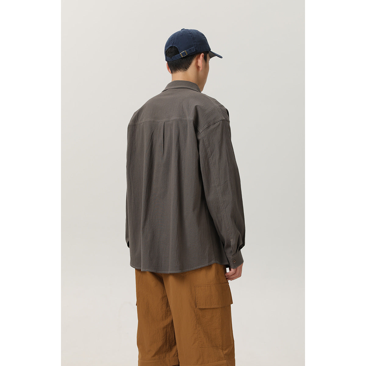 Rear view of a man wearing a charcoal gray button-up shirt with a back yoke and brown cargo pants.