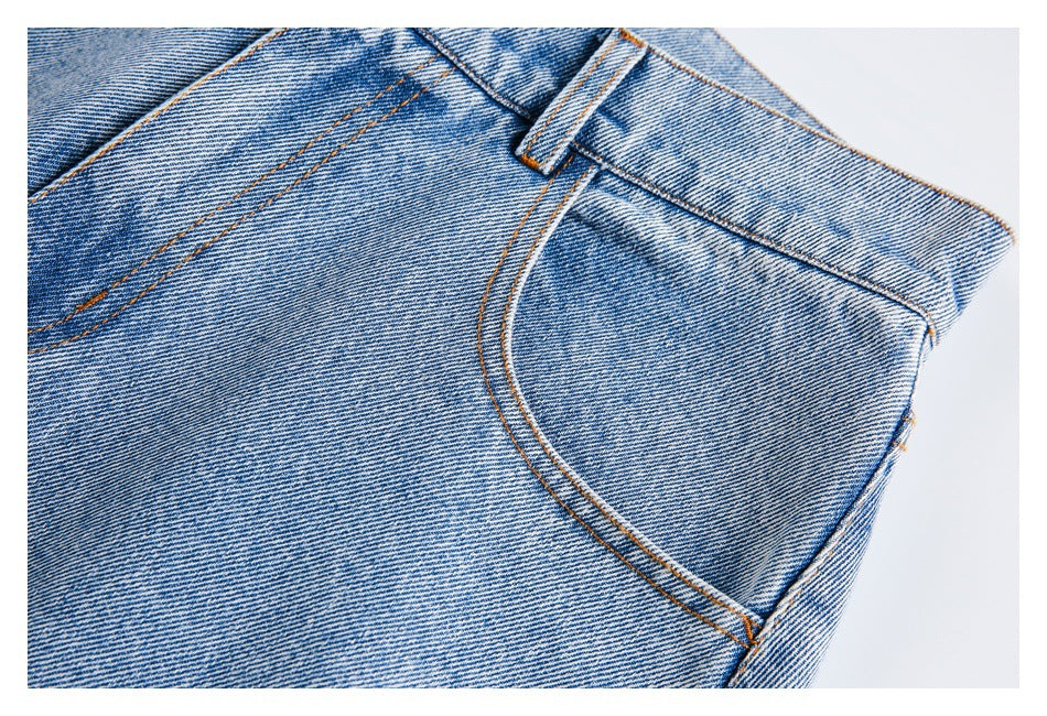 Close-up of a front pocket and belt loop on light-wash jeans, showing contrast stitching and denim texture.