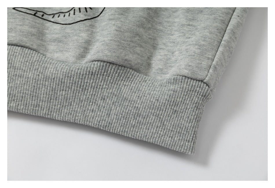 Close-up of a heather gray sweatshirt's wide ribbed waistband with part of a black graphic visible above it.