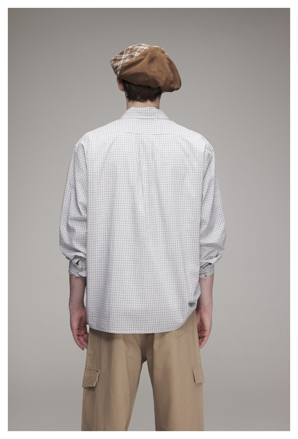 Rear view of a model wearing a light gray checked shirt and tan cargo trousers.