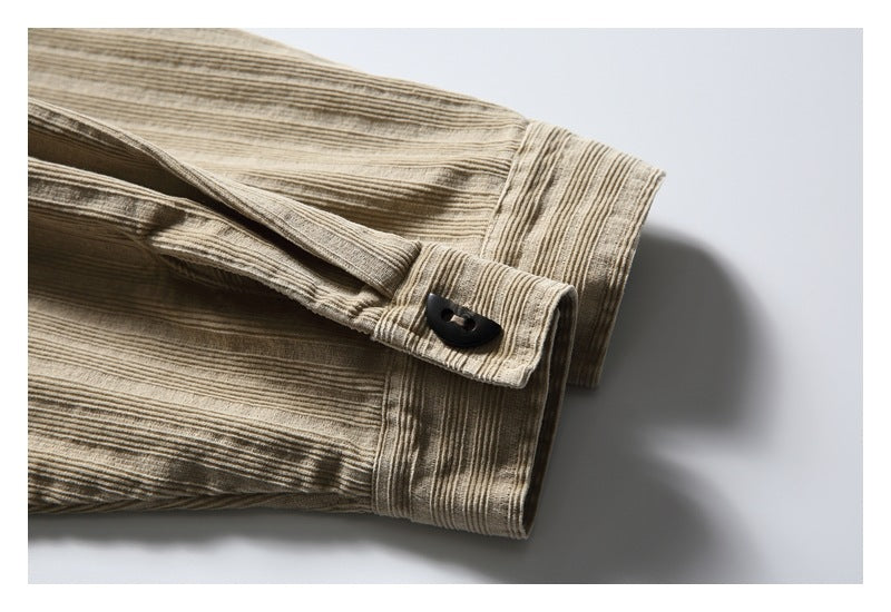 Close-up of a beige striped garment cuff with a black button.