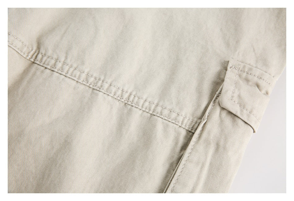 Close-up of light beige trousers showing a side seam and a small flap pocket.