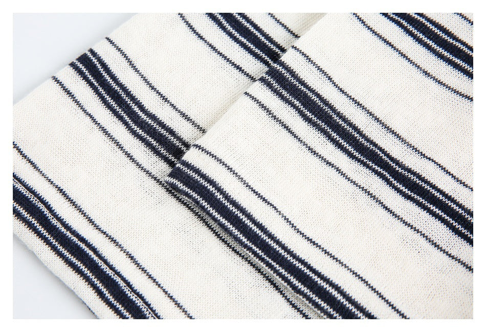 Close-up of cream knit fabric with narrow and broad navy horizontal stripes.