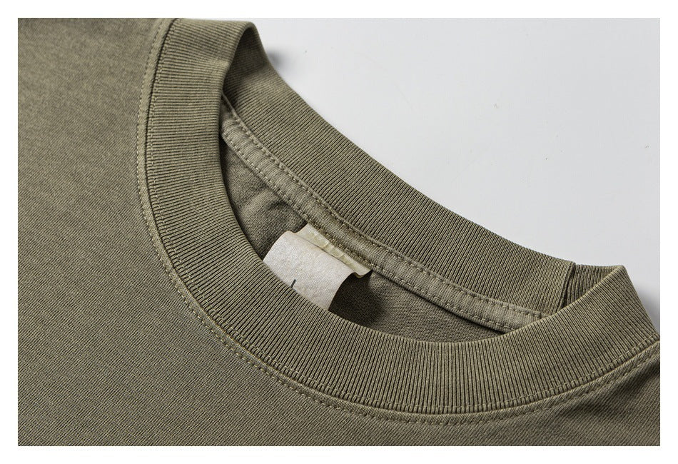 Close-up of the olive T-shirt’s ribbed crew neckline, stitching, and inner neck label.