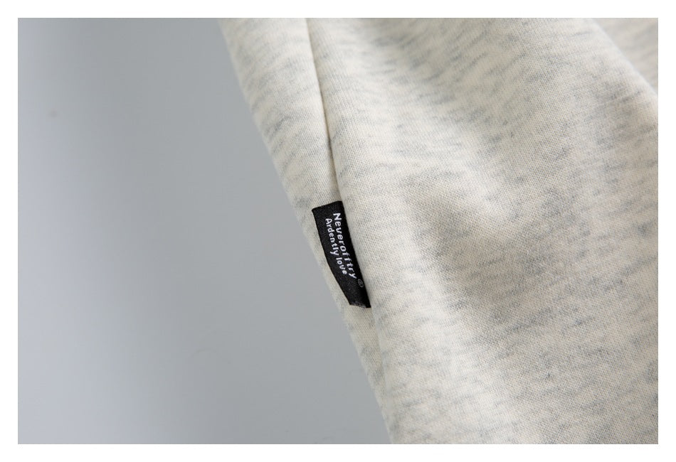 Close-up of light gray heathered fabric with a small black woven label bearing white English text.