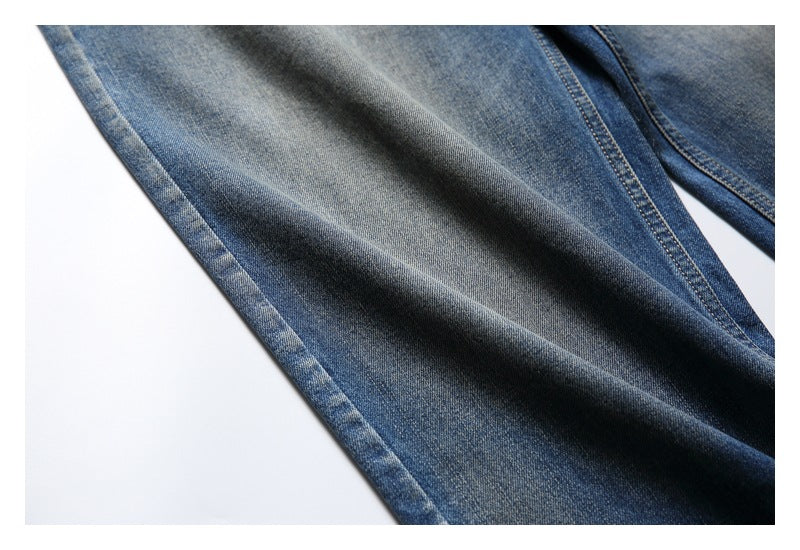 Close-up of a blue denim jeans leg with pronounced gray-blue fading and a stitched seam.
