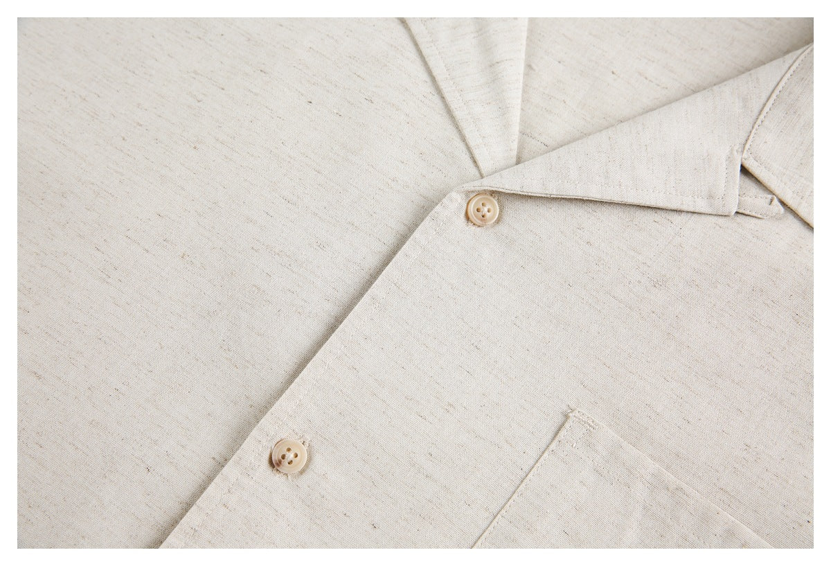 Close-up of the cream shirt's front buttons, open collar, and chest pocket edge.