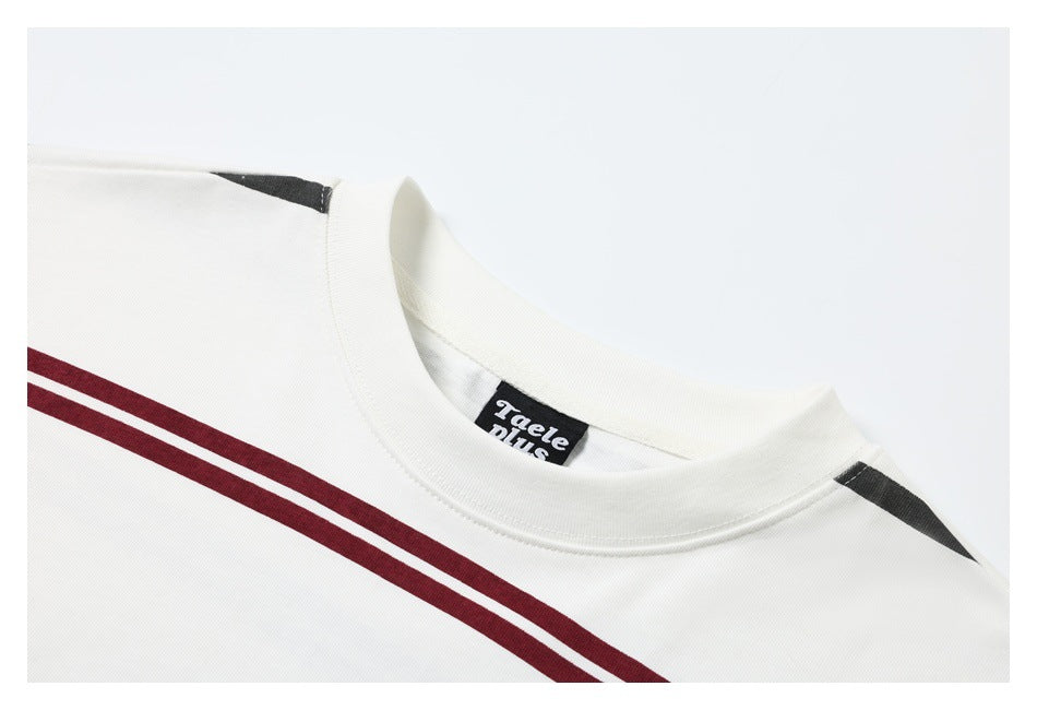 Close-up of an ivory crew neckline with burgundy chest stripes, dark shoulder accents, and a sewn label.