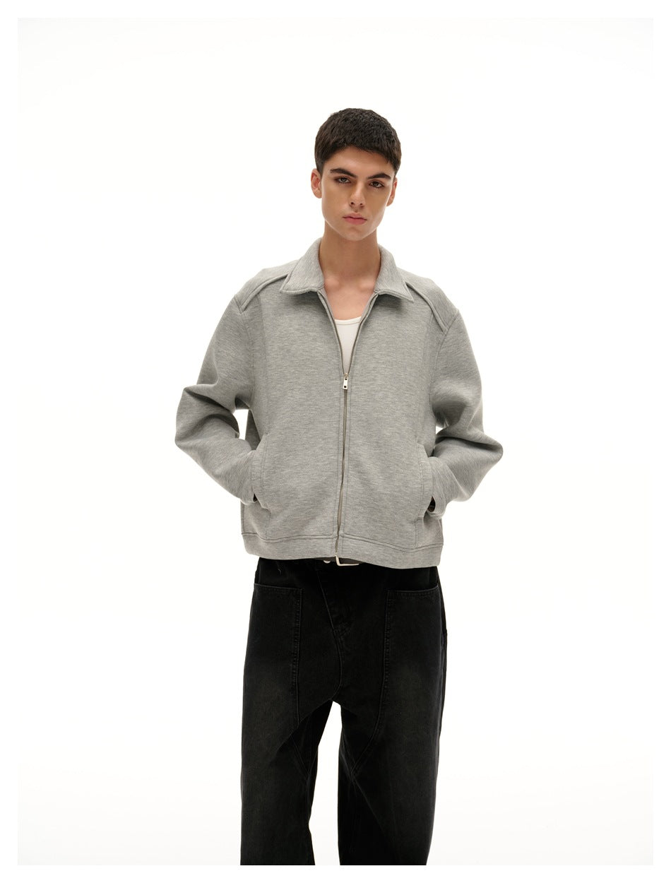 Front view of a model wearing a light gray zip-front jacket with a pointed collar and black pants.