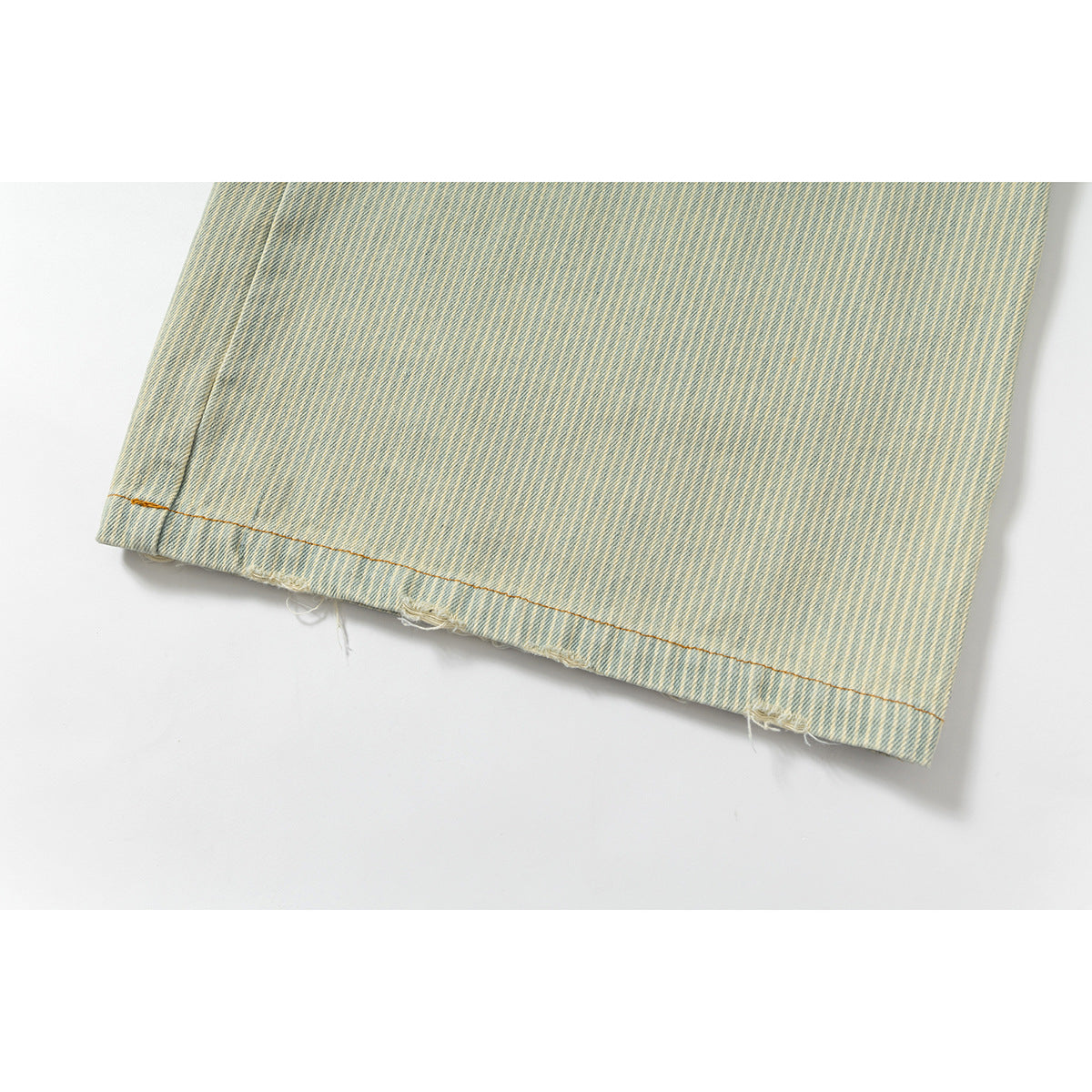 Close-up of the hem of pale blue striped shorts, with loose frayed threads along the edge.