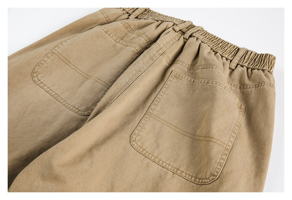 Tan pants laid flat, shown from the back with two patch pockets and an elastic waistband.