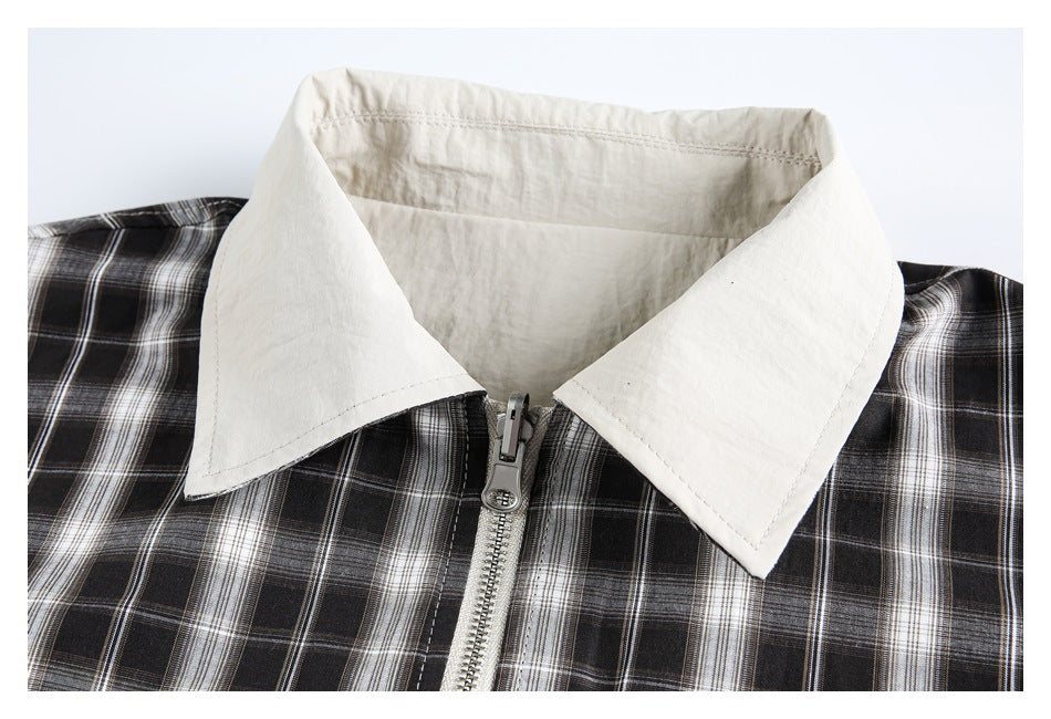 Close-up of the jacket’s light pointed collar and silver front zipper against black-and-white plaid.
