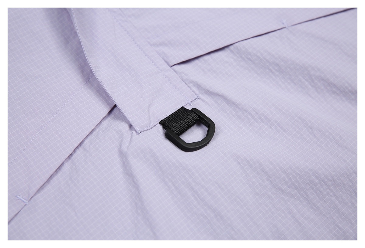 Close-up of a black D-ring attached to a lavender grid-patterned garment panel.