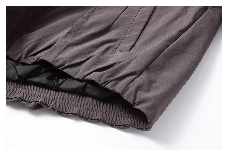 Close-up of a dark gray jacket's gathered elastic hem and pocket.
