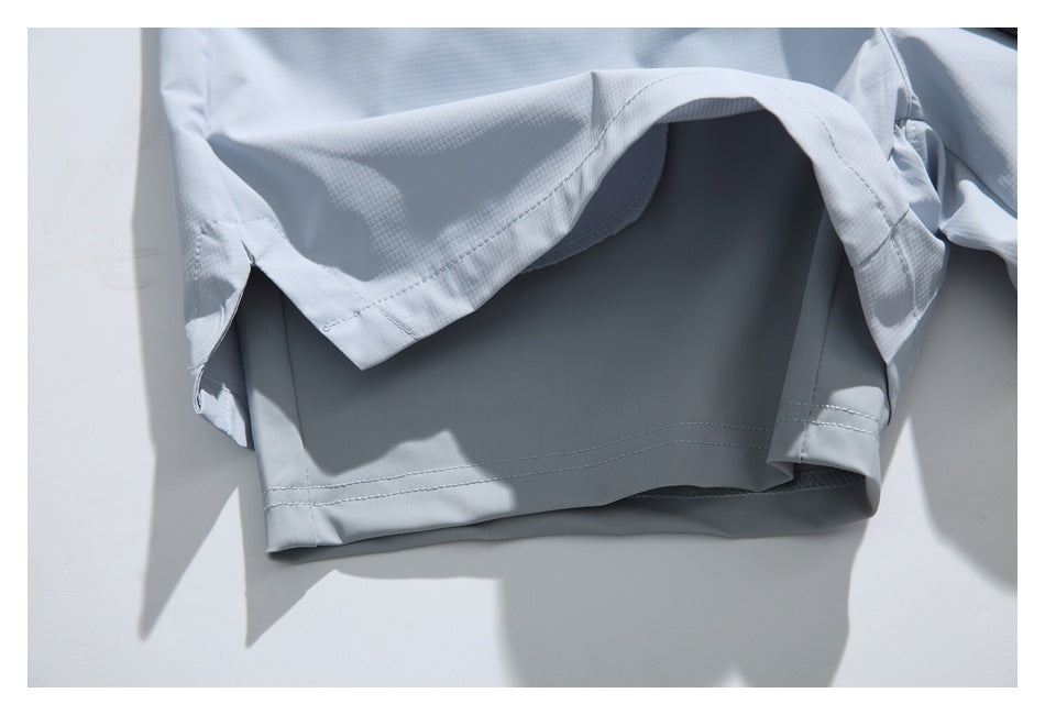 Close-up of the hem and stitched seams of a pale blue-gray garment laid flat.