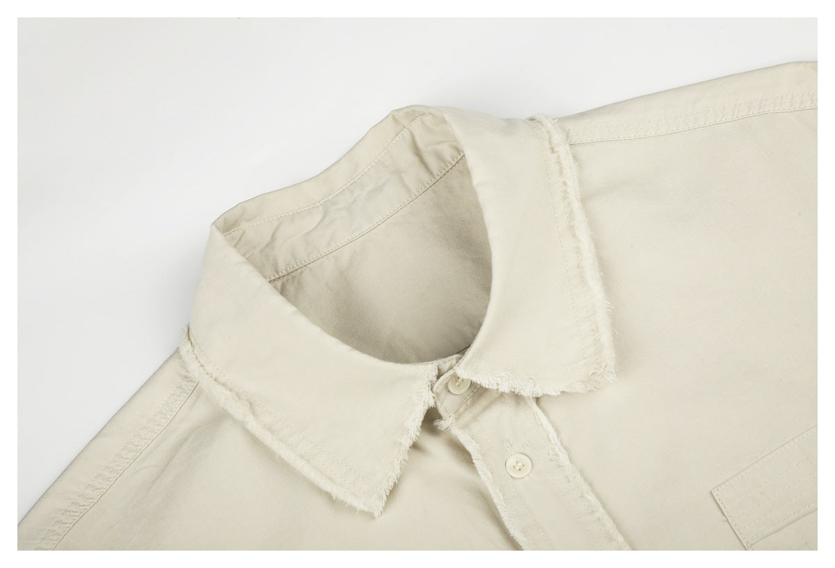 Close-up of the ivory shirt’s pointed collar, frayed edges, buttons, and shoulder stitching.