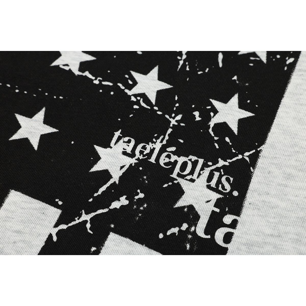 Close-up of a black-and-white star and distressed stripe print with English lettering on a light gray T-shirt.