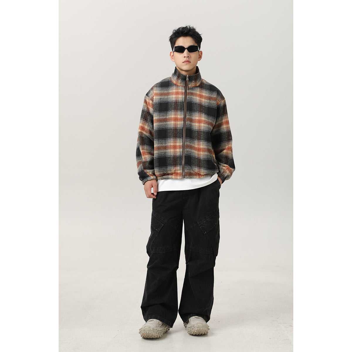 Model wears a zipped black, gray, and rust plaid jacket with a stand collar.