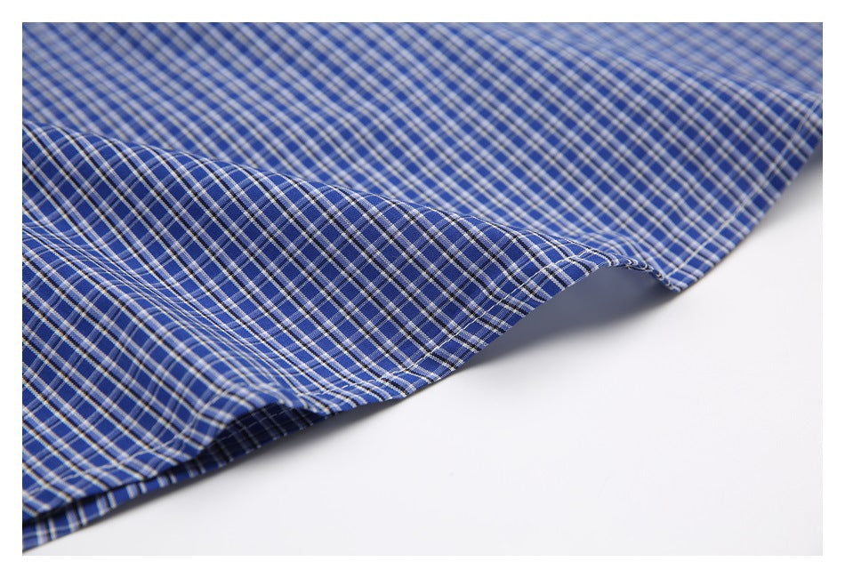 Close-up of blue plaid fabric showing its pattern and finished edge against a white surface.