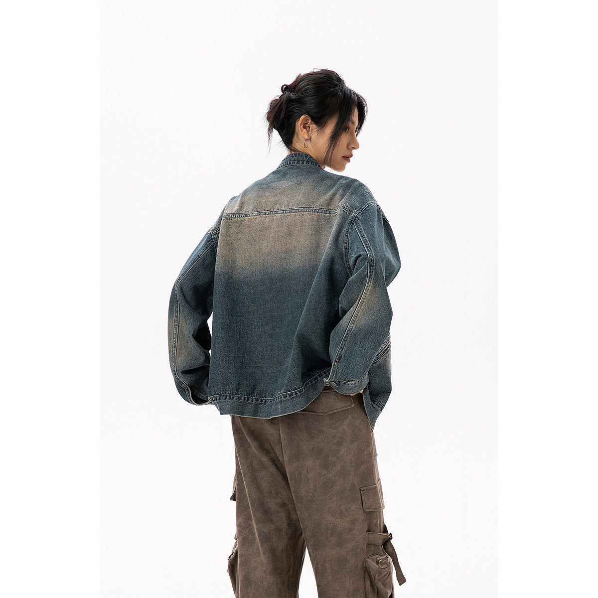 Rear view of a model wearing an oversized faded blue-gray denim jacket with a plain back panel.