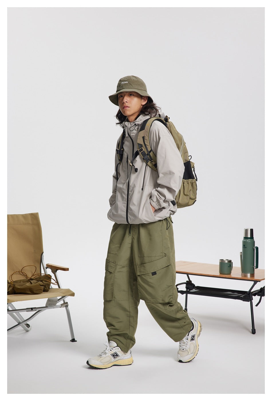 Full-length front view of a person in a light gray hooded jacket and olive cargo pants.