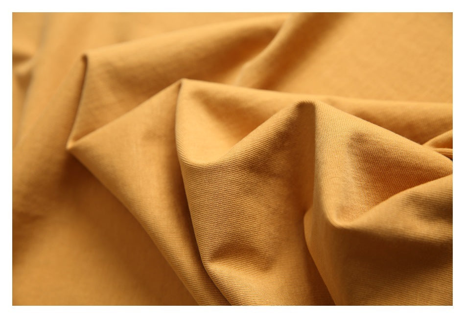 Close-up of the mustard-gold shirt fabric gathered into soft folds.