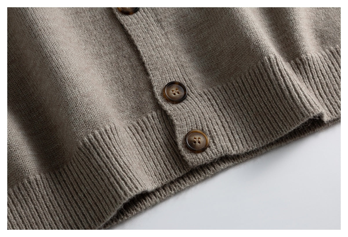 Close-up of a taupe cardigan hem with ribbed edging and three brown buttons.