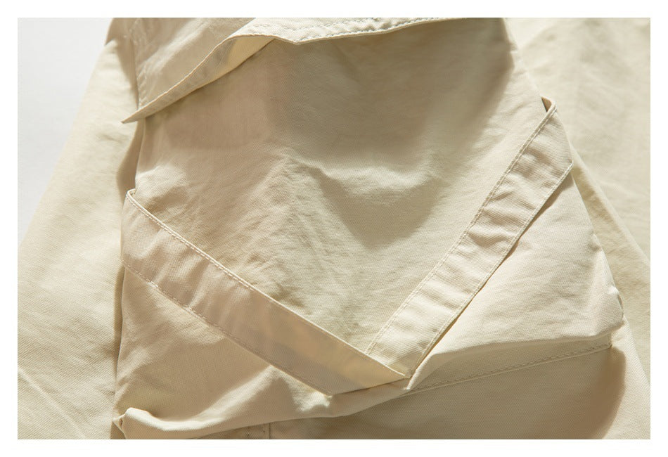 Close-up of a cream-beige trouser pocket with a wide fabric flap and visible stitching.