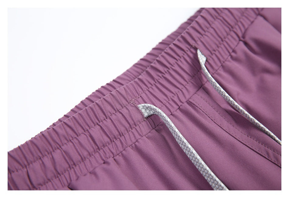 Close-up of the gathered elastic waistband and gray drawstrings on mauve pants.