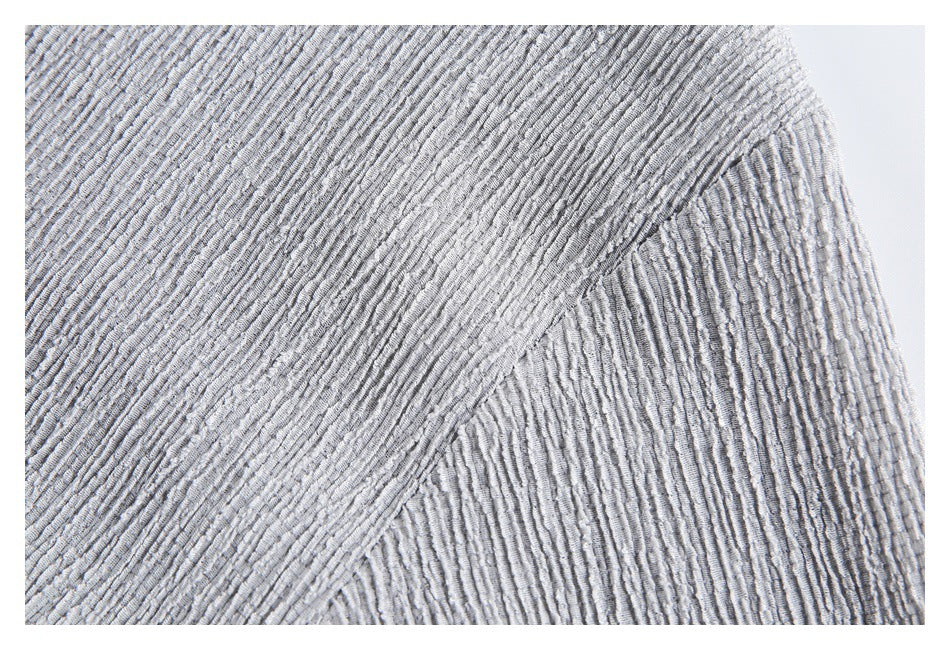 Close-up of the light gray shirt's textured sleeve and curved underarm seam.