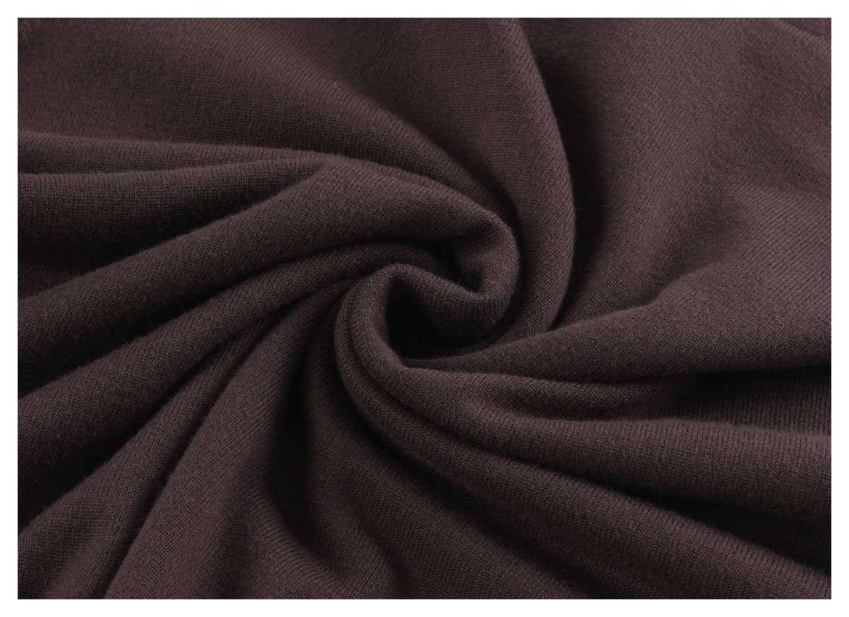 Close-up of dark brown knit fabric gathered into soft folds, showing its fine texture.