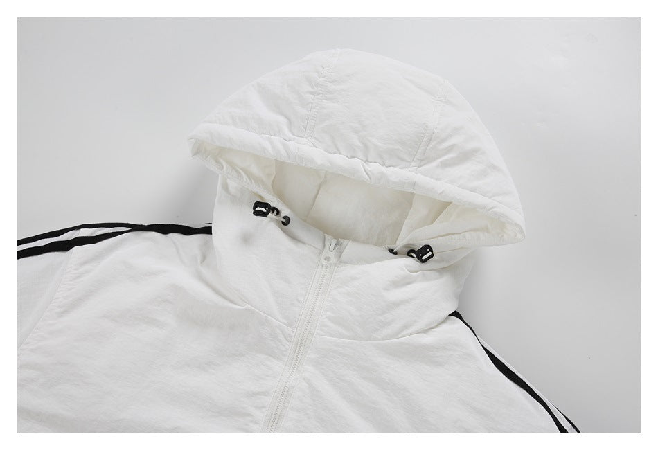 Upper front of a white jacket laid flat, showing its raised hood, zipper, drawcord toggles, and black shoulder stripes.
