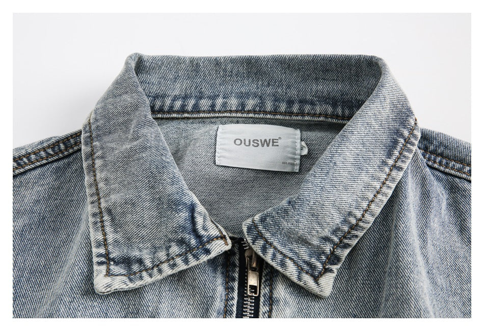 Close-up of a light-wash denim jacket collar, front zipper, and sewn-in neck label.