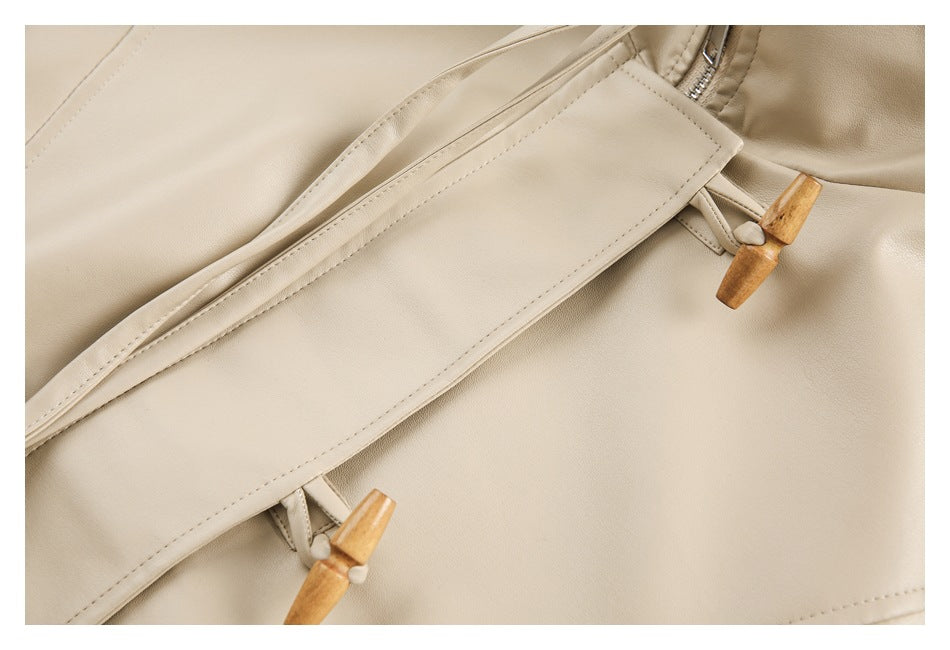 Close-up of a cream jacket’s front placket with wooden toggle fasteners and visible stitching.