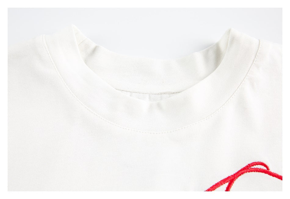Close-up of the white T-shirt's ribbed crew neckline and a small section of red embroidery.