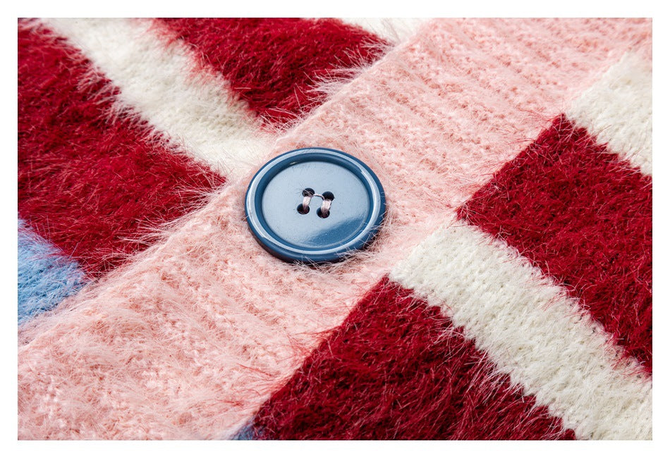 Close-up of a blue button on the pink, burgundy, and white fuzzy striped cardigan.