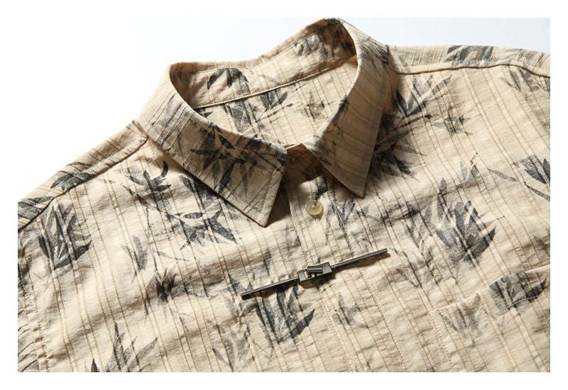 Close-up of the shirt's pointed collar, top button, dark botanical print, and silver front clasp.