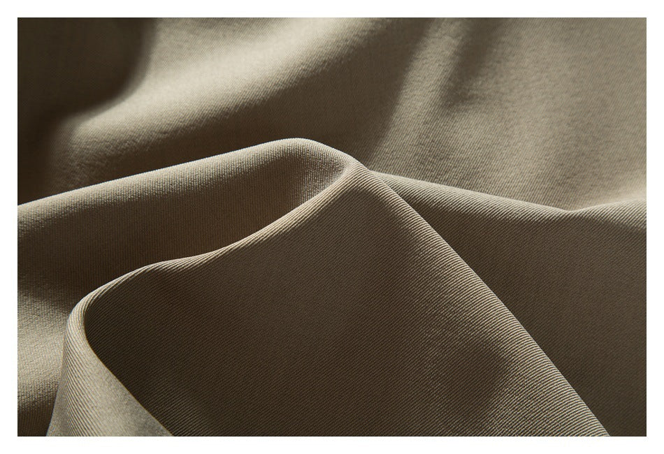 Extreme close-up of taupe trouser fabric folded to show its fine diagonal weave.