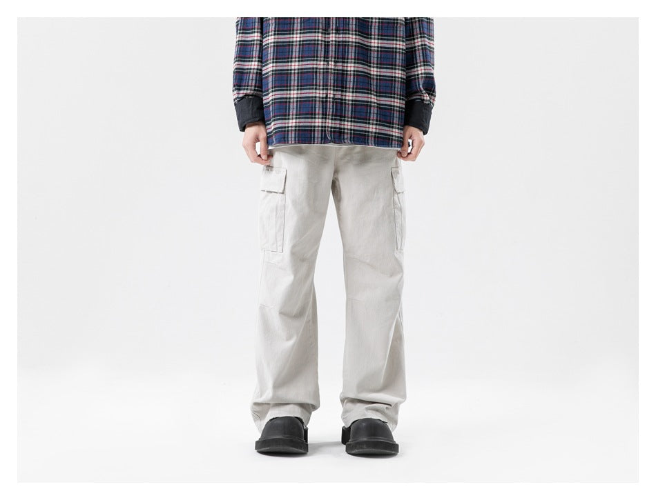 Model wearing beige cargo pants with a plaid shirt and black chunky shoes, front view
